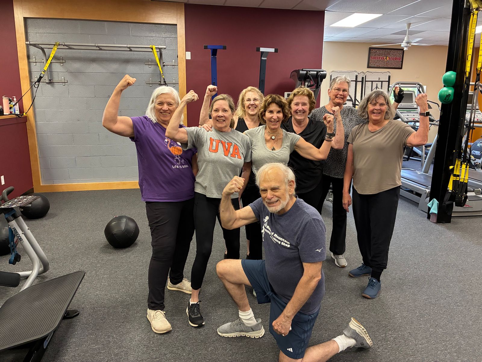 Seven members flex for a group photo in the studio, one kneeling in front
