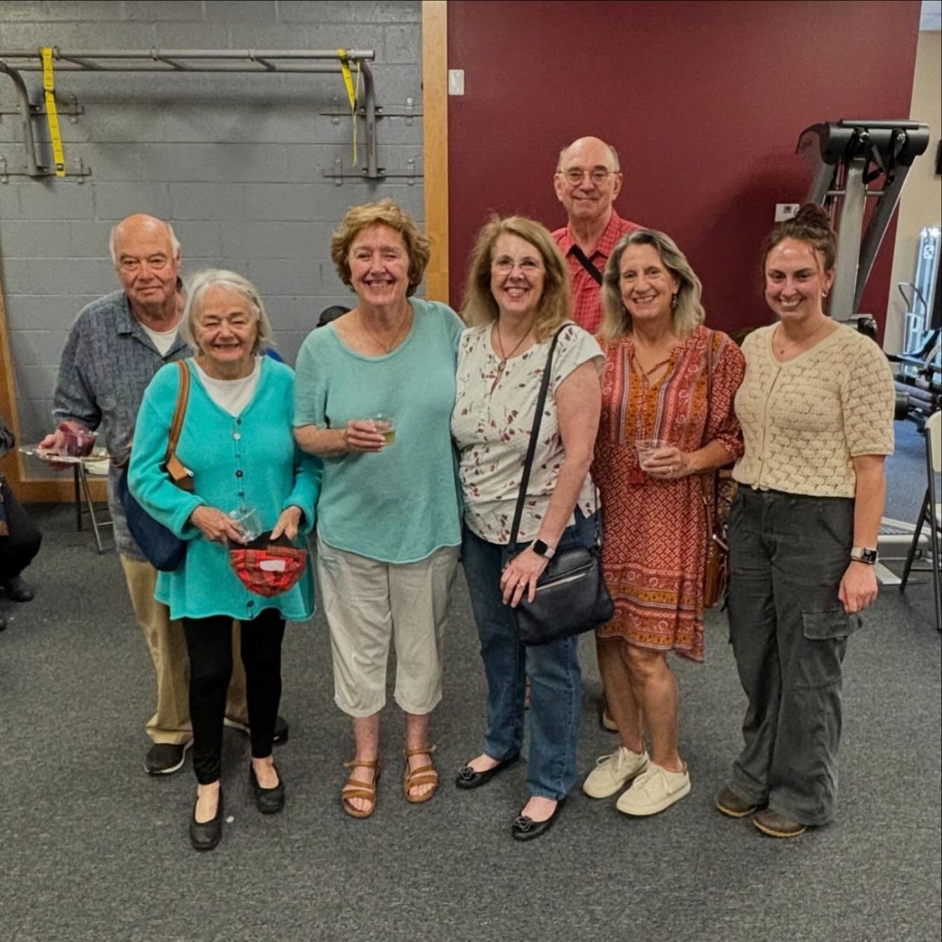 Seven members smile together, drinks in hand, at a studio open house