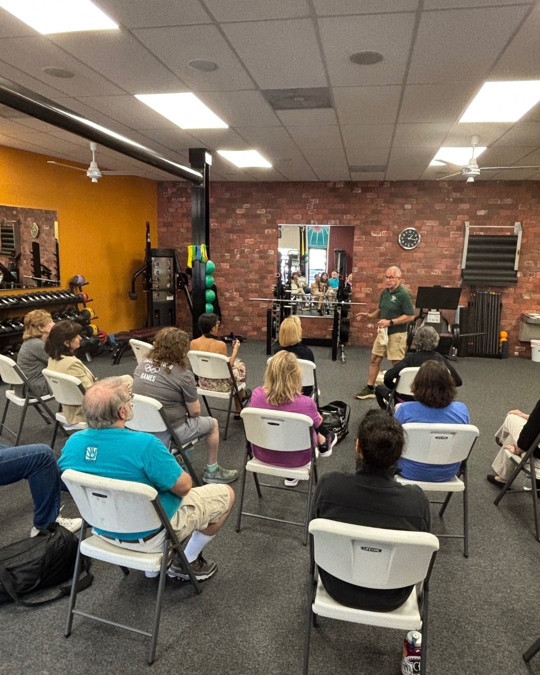 Members on folding chairs listen to a guest speaker at a workshop in the studio